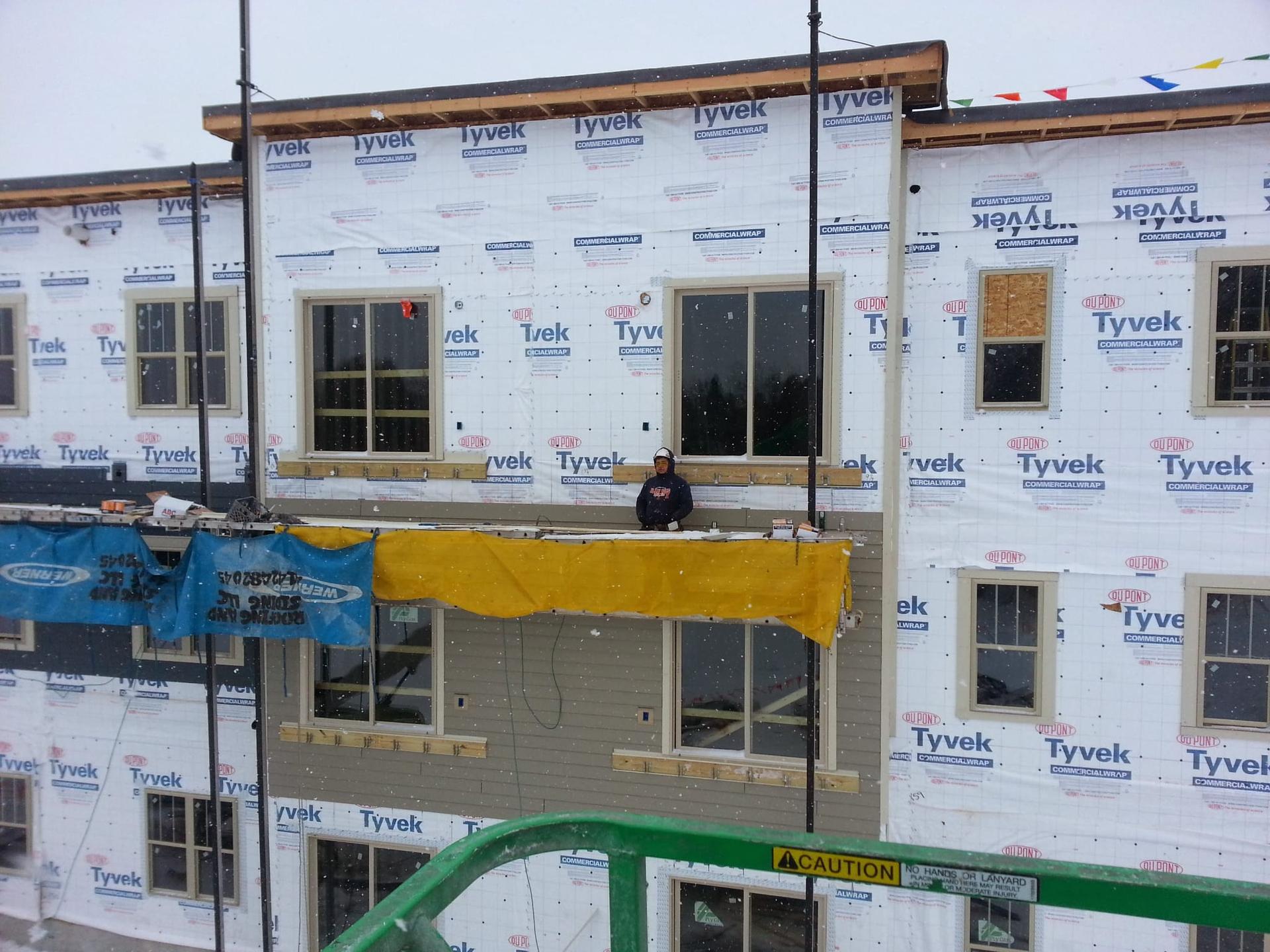 Workers installing siding on multi-family building in winter